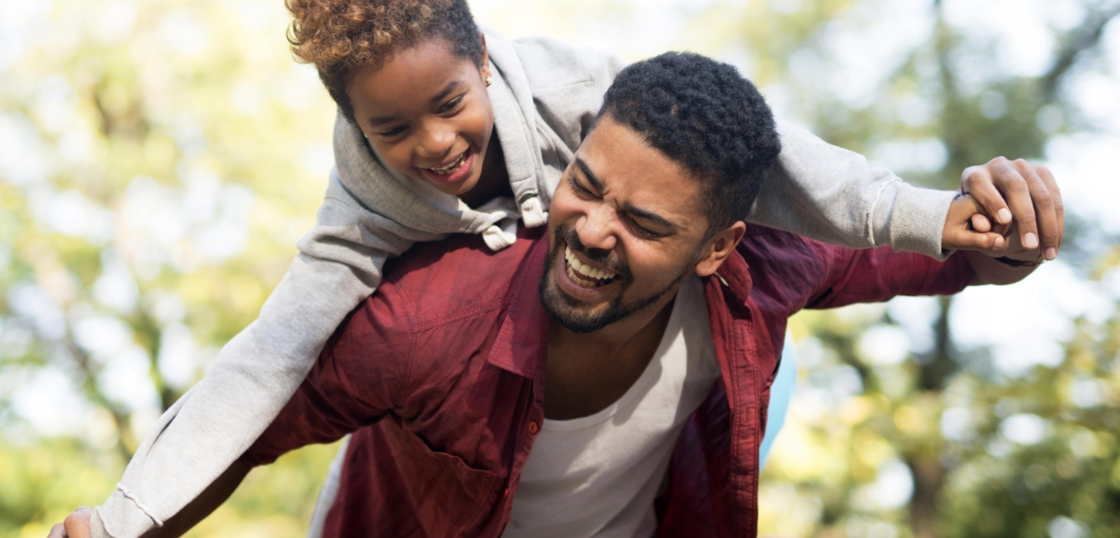 father carrying daughter on back