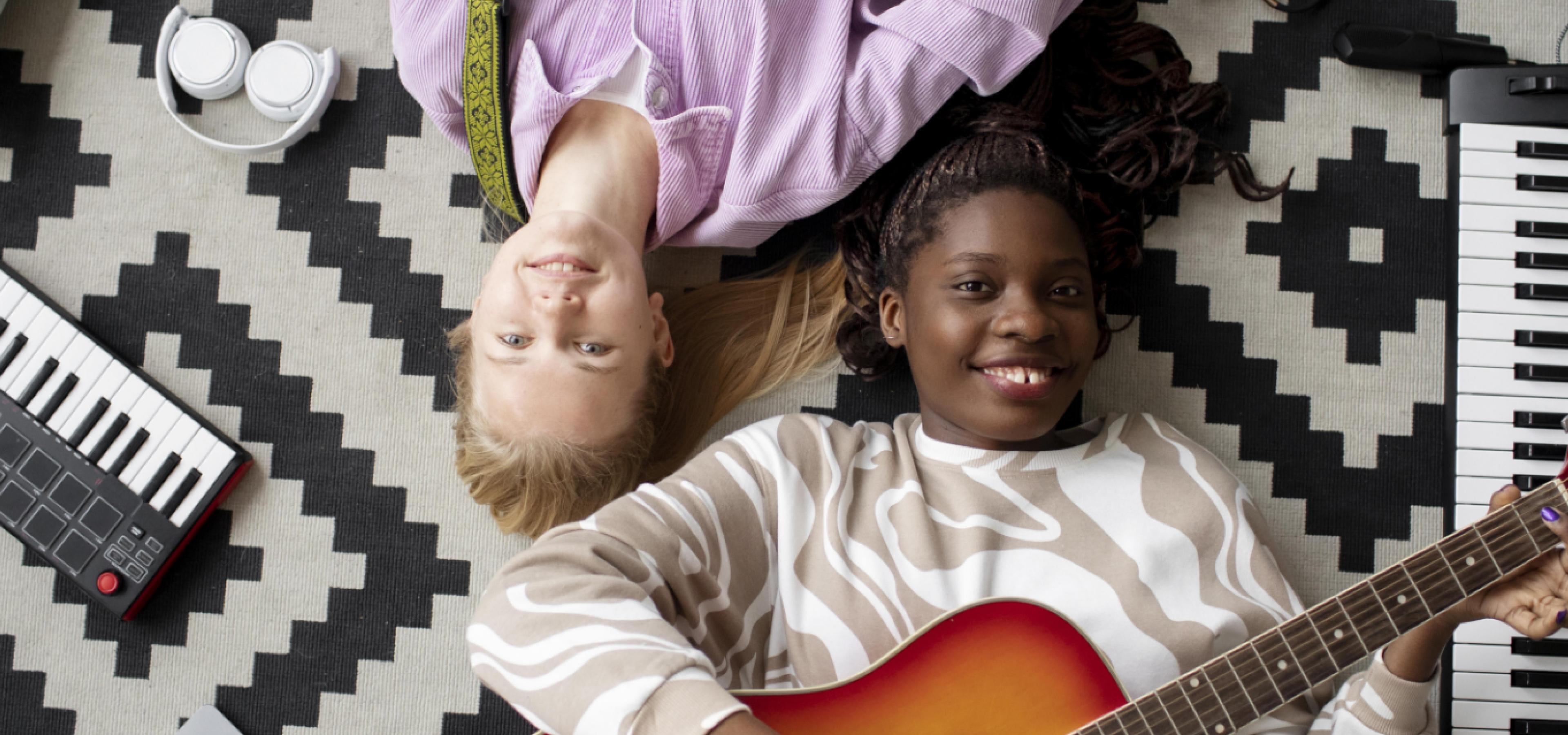 young women playing guitar on floor